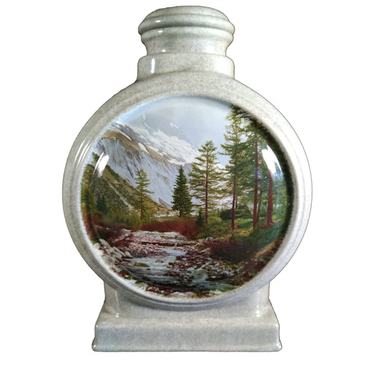 A beautiful large sized cremation ceramic urn with a decoration of a scene of a mountain stream surrounded by trees and mountains with a granite-look finish.