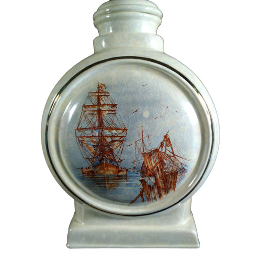 A beautiful large sized cremation ceramic urn with a decoration of a scene of a tall mast ship in a fishing harbour with a gold highlight and mother-of-pearl finish.