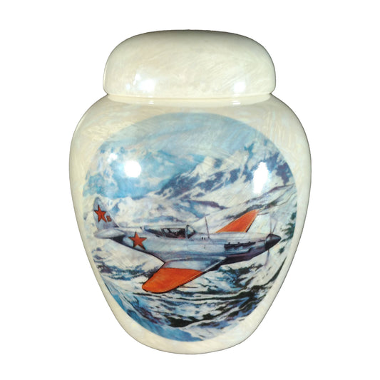 A beautiful small-sized cremation ceramic keepsake urn with a decoration of a airplane with Russian markings flying over snow-capped mountains with a mother-of-pearl finish.