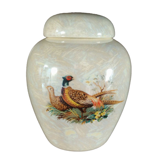 A beautiful small-sized cremation ceramic keepsake urn with a decoration of a pair of pheasants in a meadow with a mother-of-pearl finish. 