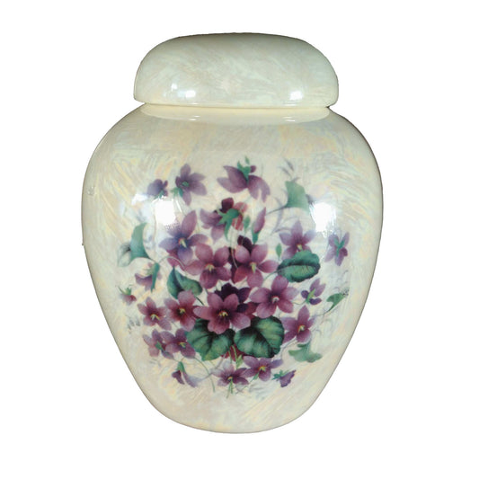 A beautiful small-sized cremation ceramic keepsake urn with a decoration of a bouquet of violets with a mother-of-pearl finish.