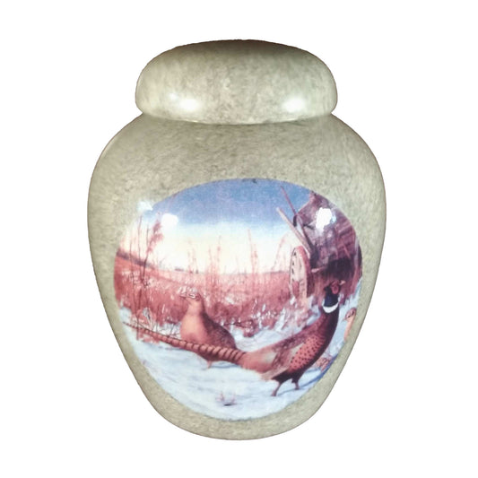 A beautiful small-sized cremation ceramic keepsake urn with a decoration of a pair of pheasants walking on snow and a antique grain wagon and field backgroundwith a granite-look finish.