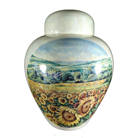 A beautiful medium sized cremation ceramic urn with a decoration of a field of sunflowers in rolling countryside scene with a mother-of-pearl finish. Front View
