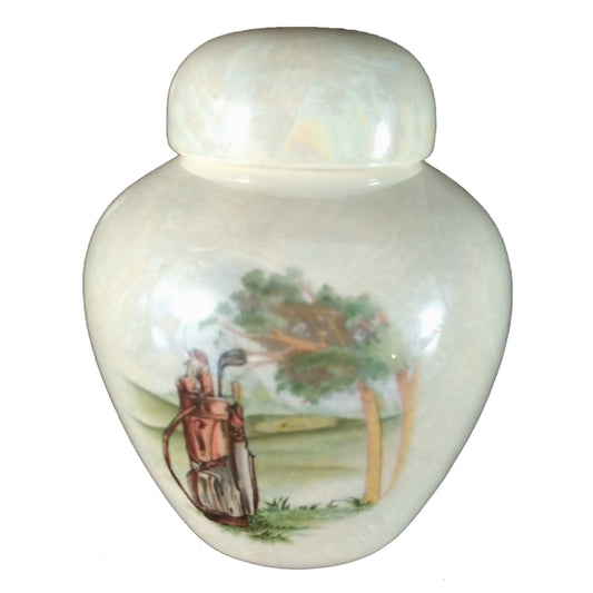 A beautiful keepsake cremation ceramic keepsake urn with a decoration of a golf bag sitting upright on a golf course with a mother-of-pearl finish.